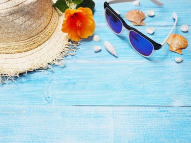 Tatil tatil arka plan. Üstten görünüm hasır şapka, güneş gözlüğü, kabukları ve Çince kopya alanı ile mavi ahşap üzerine çiçek gül. 