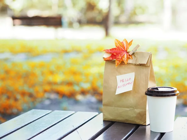 秋天吃早饭 公园的木桌上有纸条和枫叶的热咖啡和棕色纸袋 — 图库照片