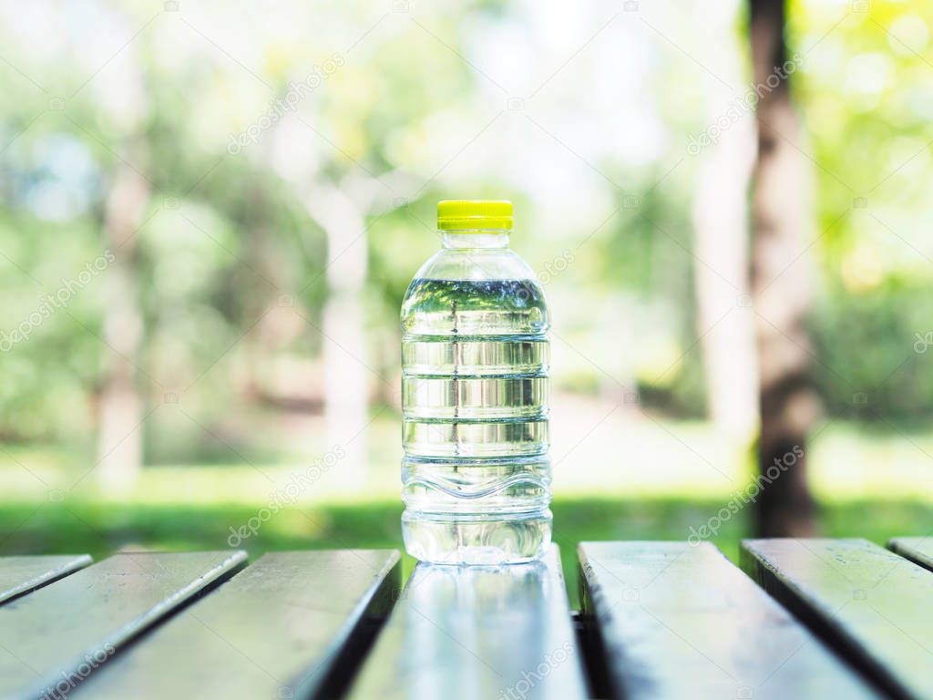 Close up plastic bottle of water on wooden table in the park. Healthy and diet concept.