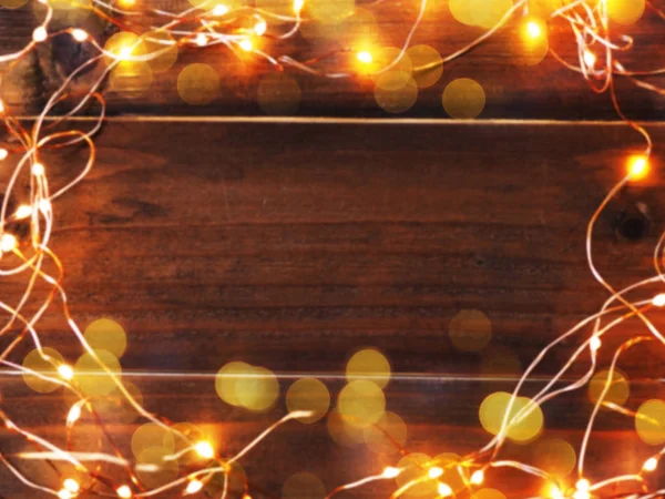 コピー スペース付きの木製グランジ テーブル Led 照明とワイヤー フレームの背景をぼかした写真を抽象化します クリスマスと新年の背景 — ストック写真