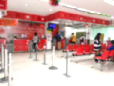 Bulanık arka plan kırmızı sandalye üzerinde oturan ve sıra postanede Tayland için bekleyen insanların.