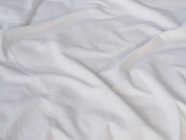 Close up crumpled white bedsheet surface in the morning at bedroom.