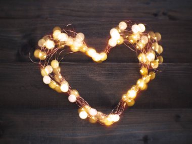 Led aydınlatma ve tel çerçeve kalp şekli kopya alanı ile kahverengi ahşap üzerine kapatın. Aşk kavramı. Sevgililer günü ve düğün arka plan.