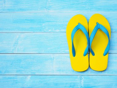Üstten Görünüm sarı kauçuk flip flop ayakkabı kopya alanı ile mavi ahşap arka plan üzerinde. Yaz tatil tatil kavramı.