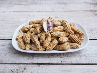 Haşlanmış fıstık beyaz plaka üzerinde yukarı grunge vintage ahşap masa üzerinde kapatın.