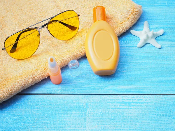 Üstten Görünüm güneşlenmek aksesuarları veya kopya alanı ile mavi ahşap arka plan ayarlamak güneş kremi. Yaz tatil tatil kavramı.