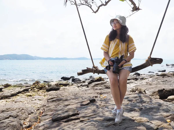 Meisje met camera zittend in houten schommel op zomer-strand — Stockfoto