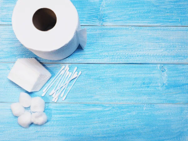 Tissue paper and cotton buds on wooden blue background.