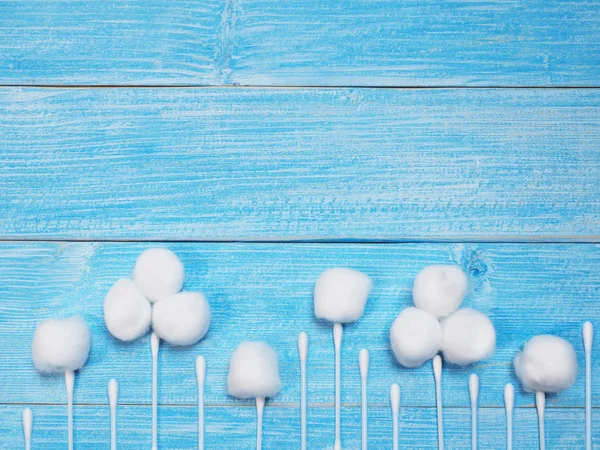 Bolas de algodón blanco absorbente y brotes de algodón en la espalda azul de madera — Foto de Stock