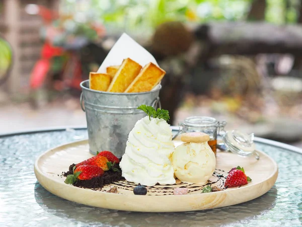 Мороженое со взбитыми сливками и клубникой на деревянной тарелке . — стоковое фото