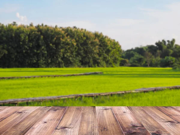 Tampo de mesa de madeira sobre fundo de campo de arroz verde . — Fotografia de Stock