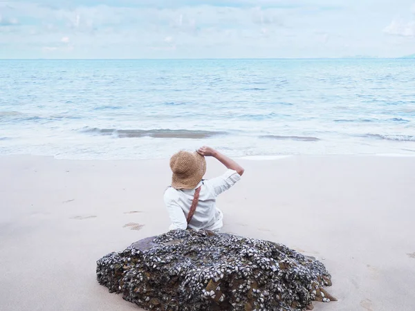 Vue arrière de jeune femme heureuse assise sur le sable et regardant vers th — Photo