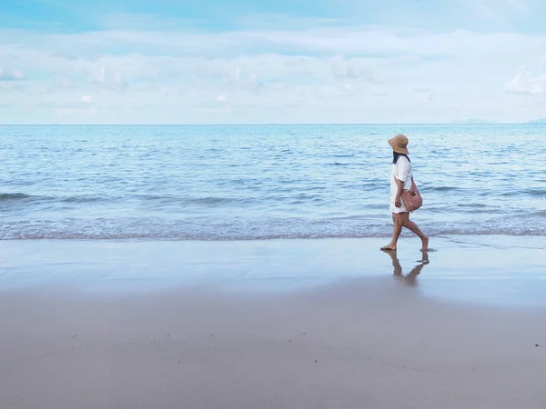 Asiatisk kvinna går ensam på sand längs stranden på morgonen — Stockfoto