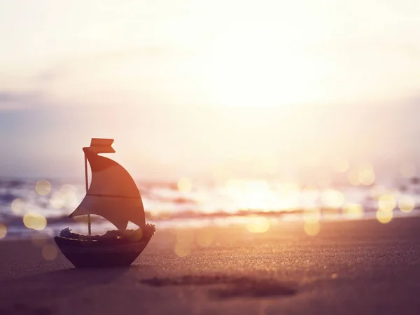 Silueta pequeño barco juguete en la arena al atardecer playa . — Foto de Stock