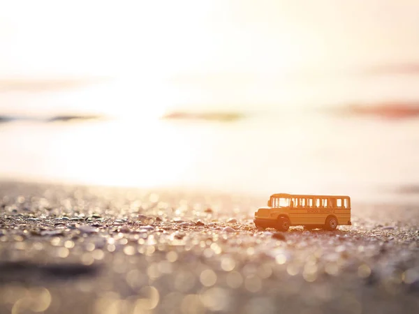 Gros plan jouet de bus scolaire jaune sur sable à la plage du coucher du soleil . — Photo