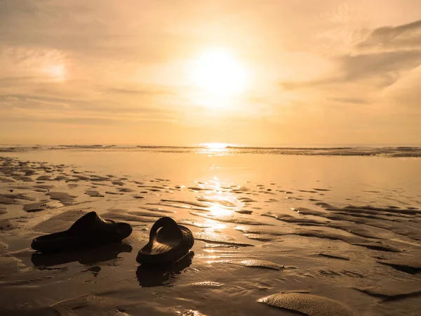 Silhouette black sandals on sand at golden sunset beach. — Stock Photo, Image