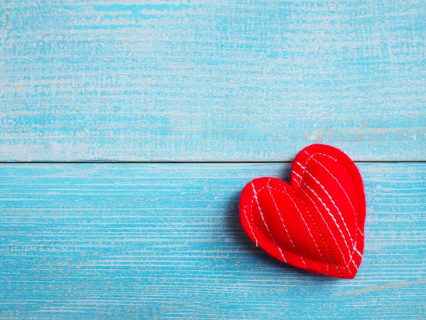 Cojín artesanía corazón rojo forma en mesa de madera azul . — Foto de Stock
