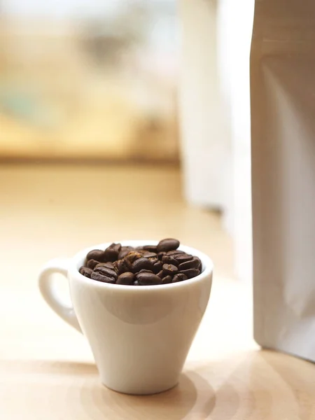 Крупним планом смажена кавова квасоля в білій чашці — стокове фото