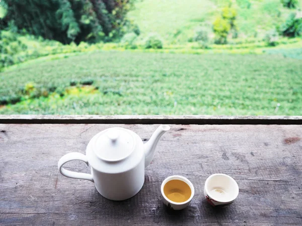 Белый чайник и чашки на винтажном деревянном столе за зеленым чаем далеко — стоковое фото