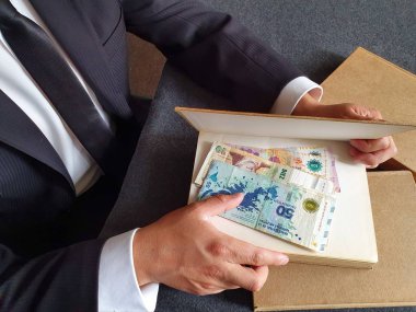 Arjantin parası ve masada kitapları olan bir iş adamının elleri. 