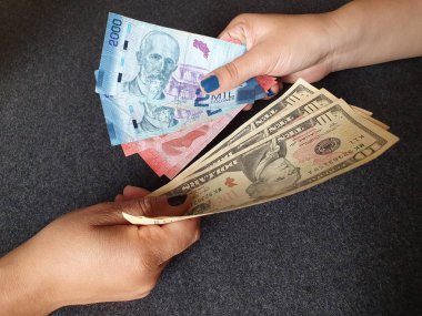 women hands exchanging Costa Rican banknotes and American dollar money clipart