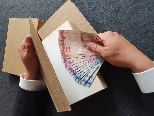 Brezilya parası ve masada kitapları olan bir iş adamının elleri. 