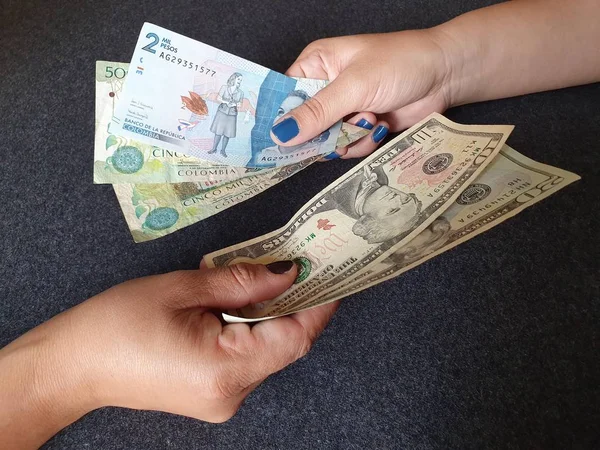Kadınlar Kolombiya banknotlarını ve Amerikan dolarlarını değiş tokuş ediyor.