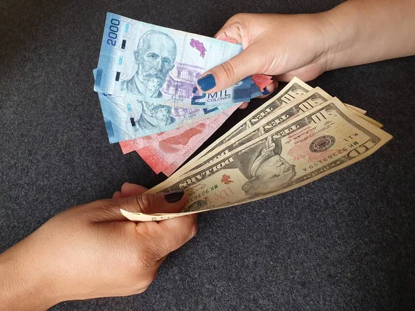 Kadınlar, Kosta Rika banknotlarını ve Amerikan dolarlarını değiş tokuş ediyorlar