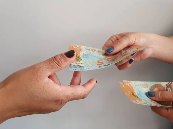 women hands paying and receiving New Zealand money