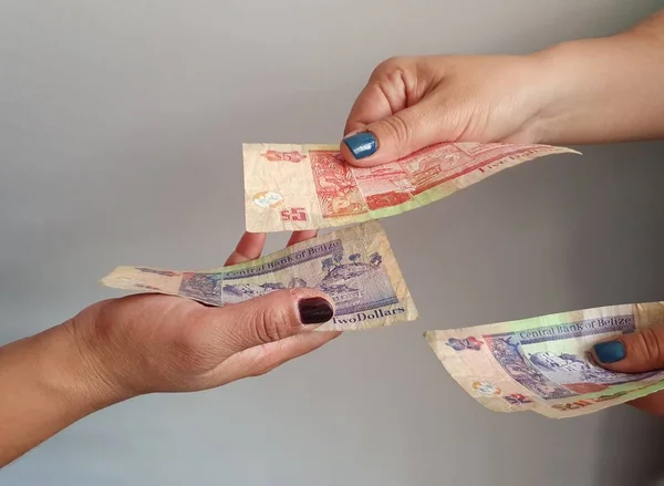 Kadınların elleri Belizean parası öder ve alır
