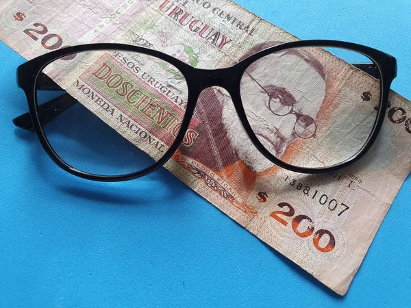 投资和促进更好的愿景 乌拉圭200比索钞票和黑色塑料框架眼镜 — 图库照片