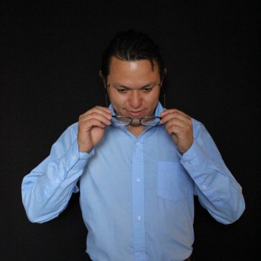 Mavi gömlekli Meksikalı adam görme yeteneğini geliştirmek için gözlük takıyor.