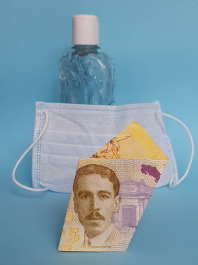 Kosta Rika banknotu 5000 kolon, yüz maskesi, jel alkollü şişe ve mavi arka plan