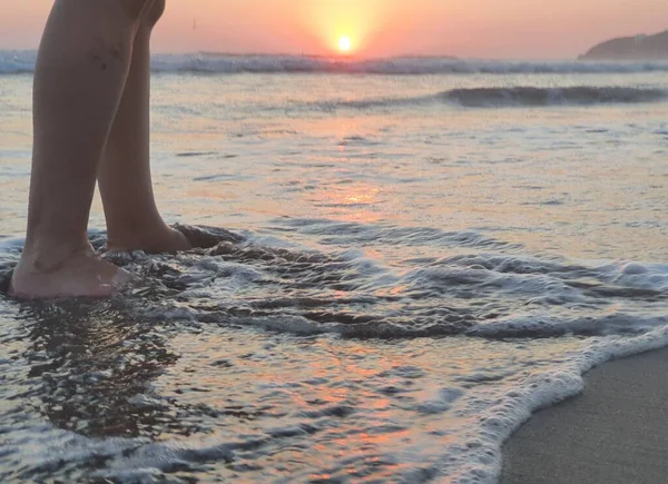 feet of a person enjoying the surf during the sunset on a beach in Acapulco, Mexico