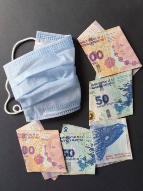 Tek kullanımlık mavi maske ve farklı değerlerde Arjantin banknotları