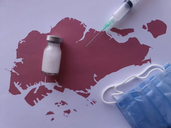 medicine bottle, mask and syringe on a sheet of paper with a map of Singapore