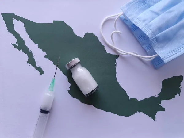 medicine bottle, mask and syringe on a sheet of paper with a map of Mexico