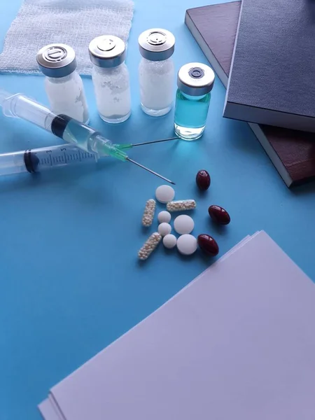 Frascos Medicamentos Seringa Comprimidos Livros Sobre Mesa Azul — Fotografia de Stock