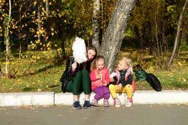 Parkta pamuk şeker yiyen kızları olan anne.