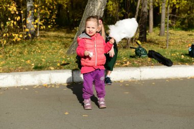 Parkta pamuk şeker yiyen kızları olan anne.