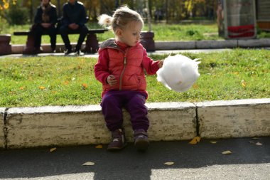 İfade dolu yüzü olan küçük güzel kız parkta pamuk şeker yiyor.