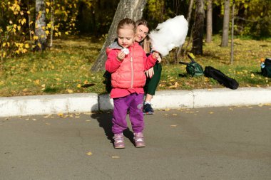 Parkta pamuk şeker yiyen kızları olan anne.