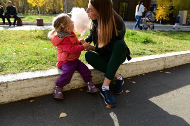 İfade dolu yüzü olan küçük güzel kız parkta pamuk şeker yiyor.
