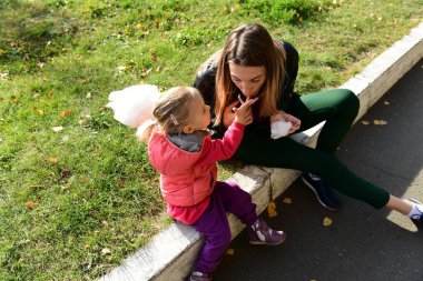 İfade dolu yüzü olan küçük güzel kız parkta pamuk şeker yiyor.