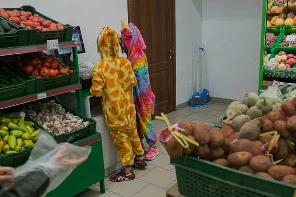 Mağazada iki çocuk, kigurumi pijamalı iki çocuk.