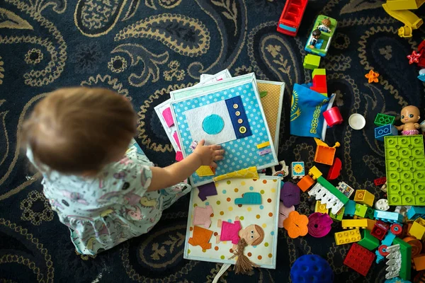 Bir çocuk yerde kitaplar ve legolarla oynuyor.