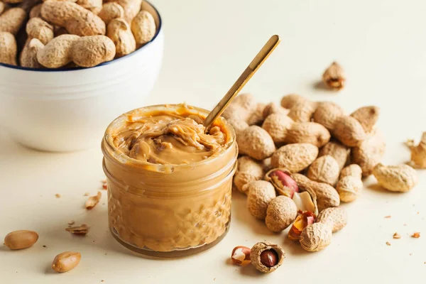 Nahaufnahme Erdnussbutter in einem Glas, eine Handvoll Erdnüsse in der Schale. Foodphoto. Kopierraum. Frühstück für Vegetarier. — Stockfoto