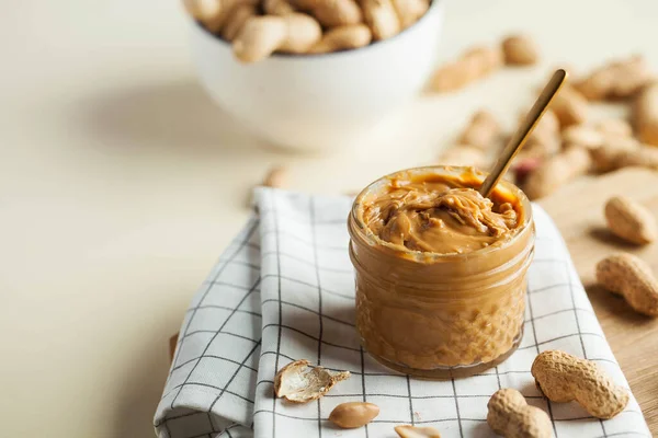 Nahaufnahme Erdnussbutter in einem Glas, eine Handvoll Erdnüsse in der Schale. Foodphoto. Kopierraum. Frühstück für Vegetarier. — Stockfoto