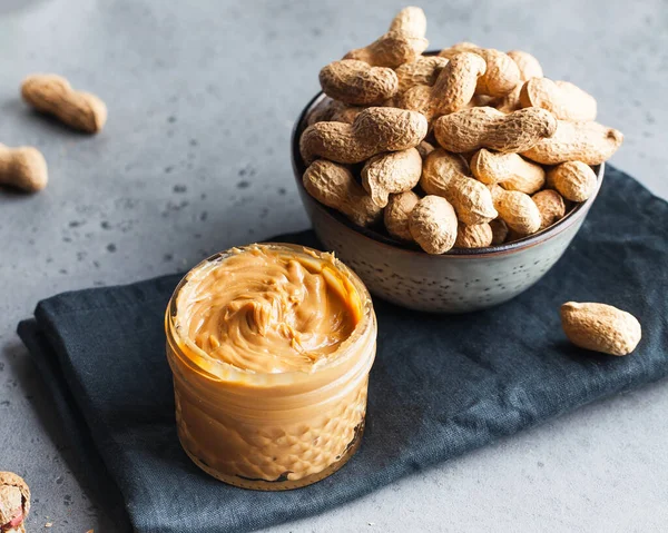 Nahaufnahme Erdnussbutter in einem Glas, eine Handvoll Erdnüsse in der Schale. Foodphoto. Kopierraum. Frühstück für Vegetarier. — Stockfoto