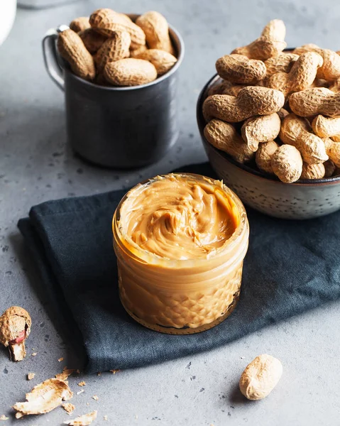 Nahaufnahme Erdnussbutter in einem Glas, eine Handvoll Erdnüsse in der Schale. Foodphoto. Kopierraum. Frühstück für Vegetarier. — Stockfoto